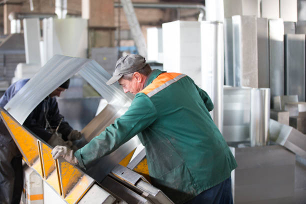 istock Two workers make metal ventilation pipes in the workshop at the factory 1299982539