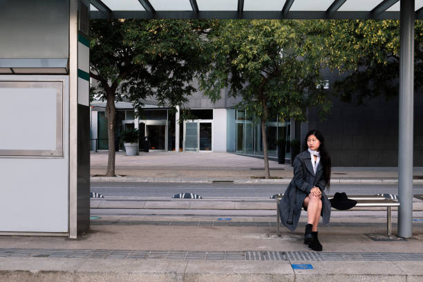 tram stop with an asian woman sitting and waiting for the train, concept of public transportation and urban lifestyle