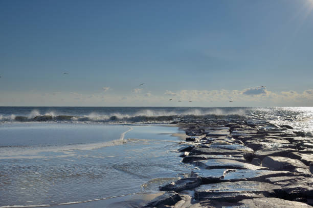 Looking out to the Atlantic Ocean along the Ocean City, MD jetty at high tide with sea level almost covering the jetty
