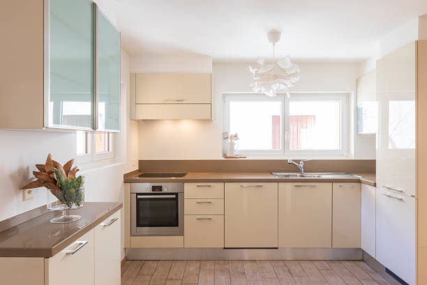 istock Clean and modern cream kitchen with large and bright windows 1299983753