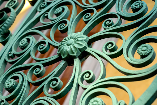 background colored wall, foreground green wrought iron, close view, no people, sunny day, side front angle view from slightly below