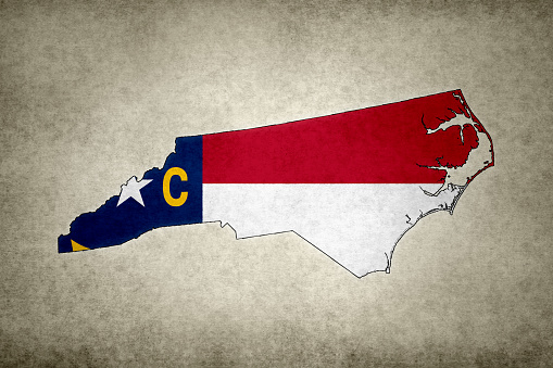 Grunge map of the state of North Carolina (USA) with its flag printed within its border on an old paper.
