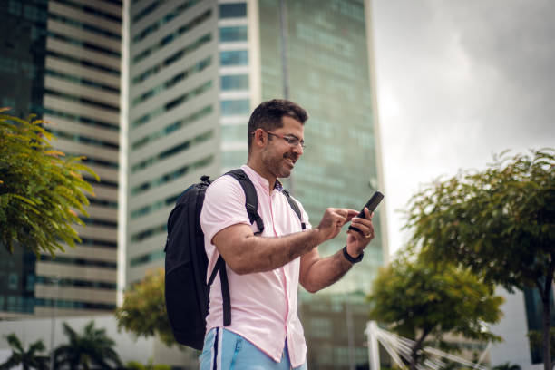 istock Smiling young man with backpack and smartphone 1299985225