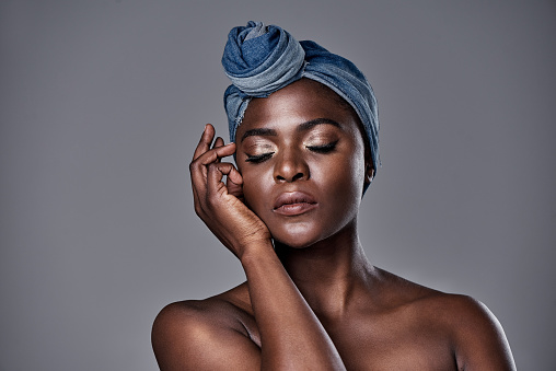 Shot of a beautiful young woman wearing a denim head wrap while posing against a grey background