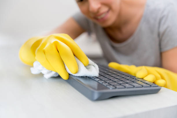 istock Woman at home cleaning the keyboard of her computer 1299988062