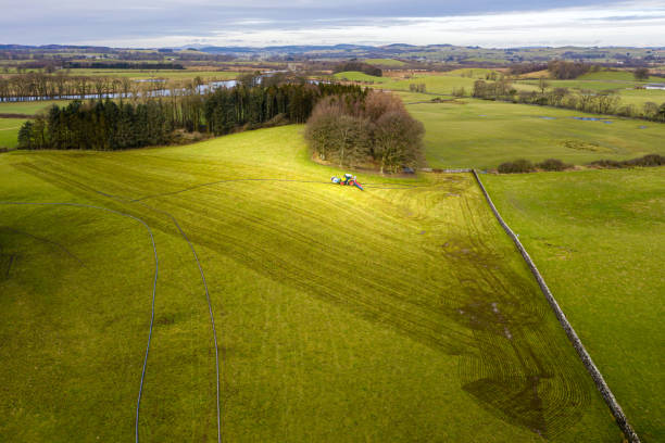 vue aérienne à angle élevé d’un drone d’un tracteur utilisant un système d’injection de boue pour pulvériser le lisier sur un champ - spreader photos et images de collection