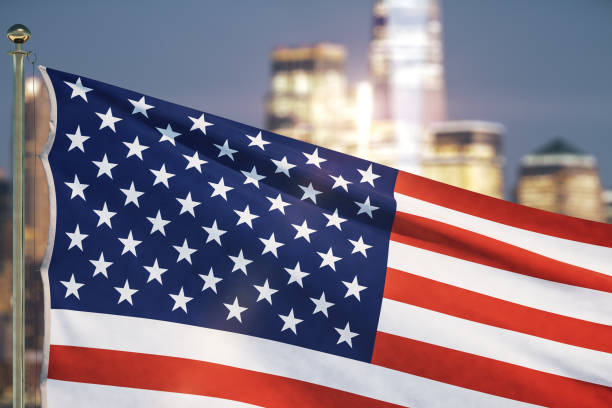 istock USA flag on blurry cityscape background at evening, close up 1299992472