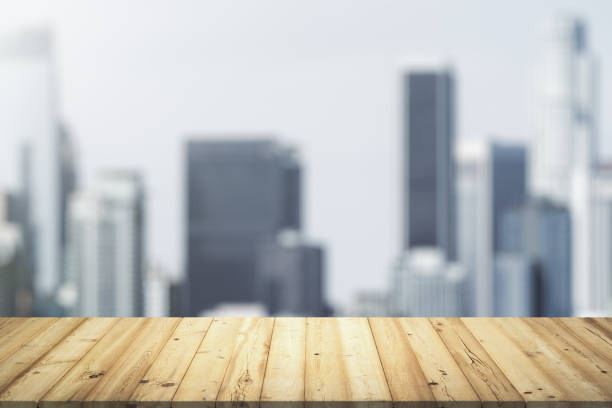 istock Wooden tabletop with beautiful blurry skyscrapers on background, mock up 1299992514