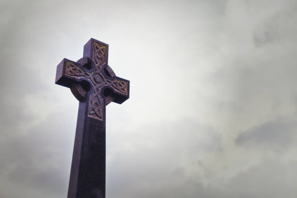 istock Tombstone Celtic cross against an overcast sky in a cemetery 1299996392