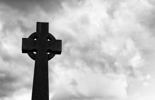 istock Tombstone Celtic cross against an overcast sky in a cemetery 1299996586
