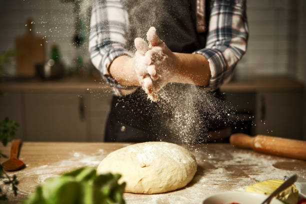 istock Young woman kneading dough ,clap hands with flour in kitchen 1299996635