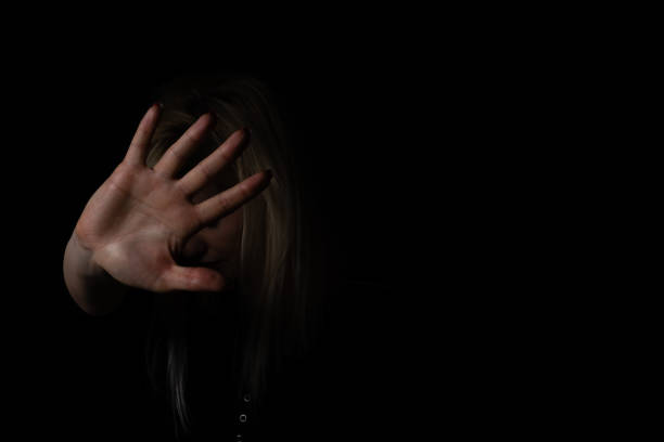 istock woman with raised hand on black background 1299998128