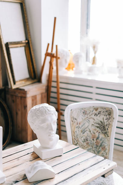 istock Interior details of home creative studio, large wooden table, easel and canvases. 1299998418