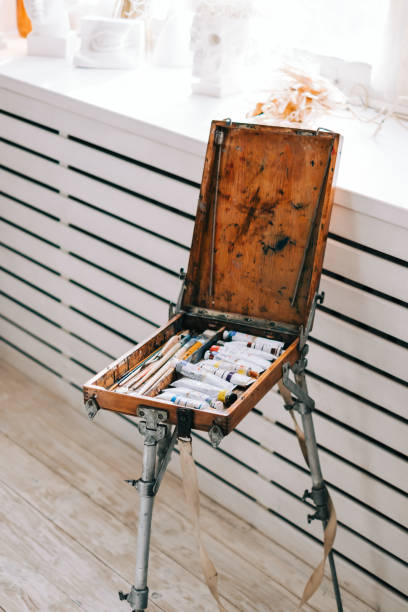 istock Rack with art paints and brushes in a wooden box at home creative studio. 1299998661