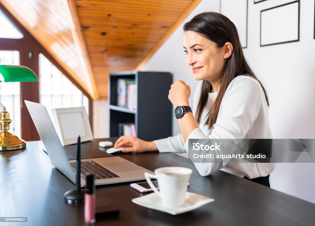A young business woman is working on laptop computer and having video conference call via computer at home office. Online call meeting. Working remotely at home. Dating Stock Photo