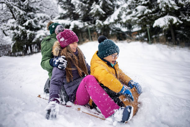 istock Three kids enjoying sledding on hill in winter. 1300001208