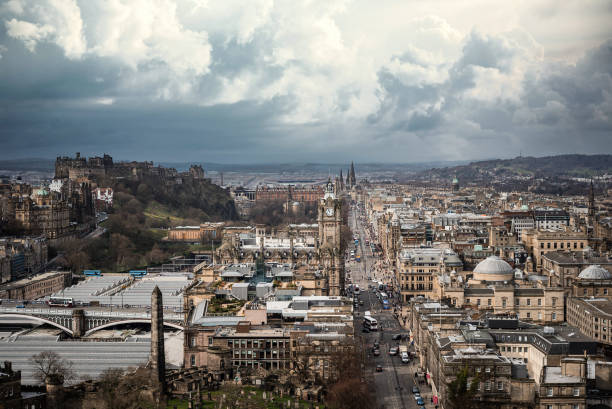 il centro di edimburgo che guarda in fondo alla principale via dello shopping street dal punto di vista aereo alto con nuvole di tempesta di tuoni che si raccolgono all'orizzonte, torre dell'orologio dell'hotel del municipio nel centro di un paesaggio urba - bridge edinburgh panoramic scenics foto e immagini stock