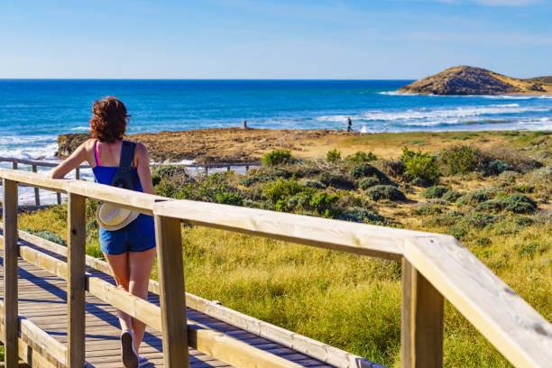 istock Woman walking on wooden path on sea shore 1300001829