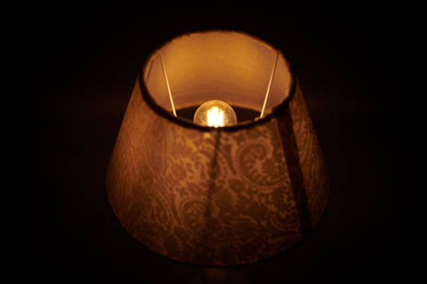 istock Incandescent lamp in round lampshade glowing in dark. 1300002869