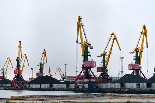 Massive harbor cranes in seaport. Heavy load dockside cranes in port, cargo container yard, container ship terminal. Business and commerce, logistics. Industrial scene.