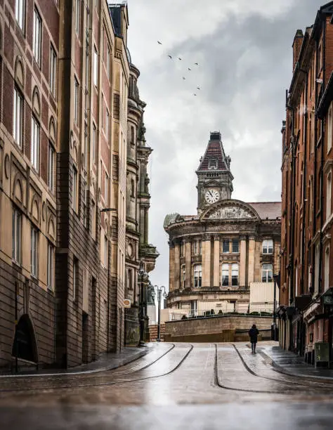 Photo of Birmingham UK city centre deserted streets during Covid-19 pandemic lockdown town hall clocktower with tram tracks in Victoria Square West Midlands stormy sky clouds and birds flying above