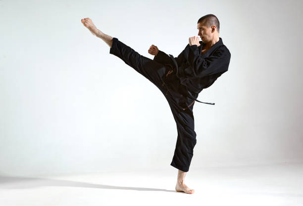 il ragazzo combattente in kimono nero mostra la tecnica kudo sullo sfondo dello studio con spazio di copia, concetto di combattimento mix - karate foto e immagini stock