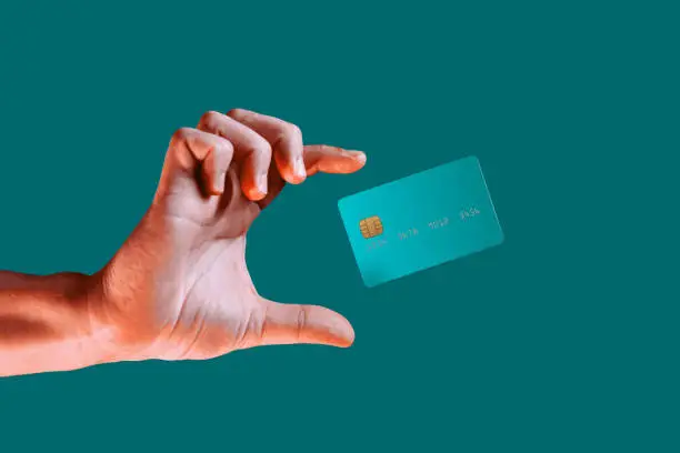 Close up male hand and levitating template mockup bank credit card with online service isolated on green background. High quality photo