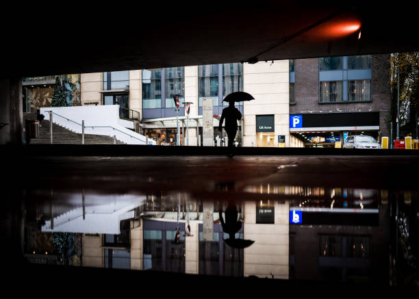 homme seul marchant par le passage inférieur inondé avec le parapluie navettant pour travailler dans l’eau d’inondation de centre-ville a reflété la silhouette reflétée en miroir la silhouette pluvieuse jour de temps violent grande flaque birming - pedestrian accident england street photos et images de collection