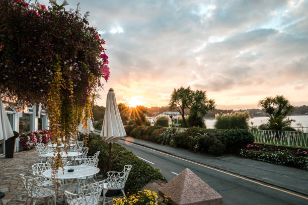 Looking down the Main Street of St Brelades Bay as the sun rises with hotels to the left and the sea front on the right st brelades bay canal isla de jersey al atardecer amanecer amanecer impresionante cielo naranja vibrante hermosa playa de arena de la costa en la noche de la mañana de la carretera del hotel nubes horizonte que refleja el sol en la ventana uk vacaciones