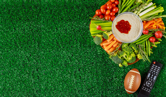 Colorful vegetable platter with football ball for american football game party. Top view, copy space.