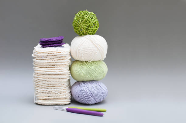 Crochet and knitting. Light green, purple, white skeins yarn and colored hooks on gray background.