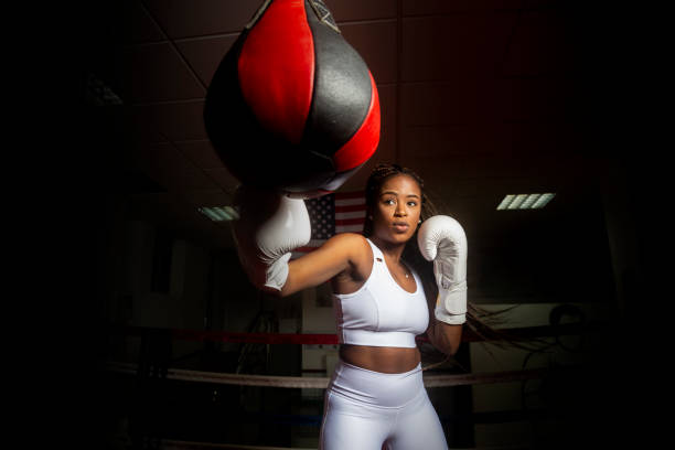joven afroamericana entrenando boxeo en el gimnasio con la bandera de los estados unidos en el fondo. - boxing womens fotografías e imágenes de stock