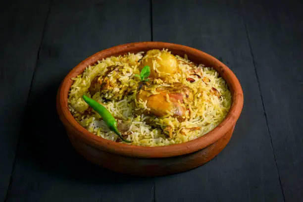 Photo of Chicken biryani on black background, Spicy indian handi biryani.