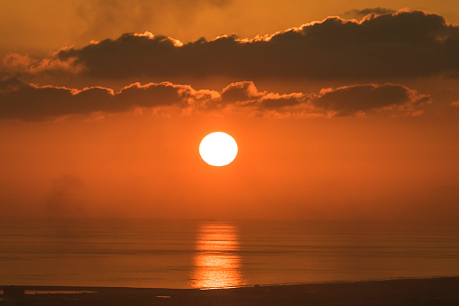 Red sun setting over the ocean in middle east arid desert