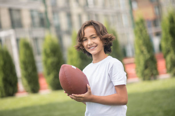 istock Dark-haired boy in a white tshirt playing with a ball 1300008938