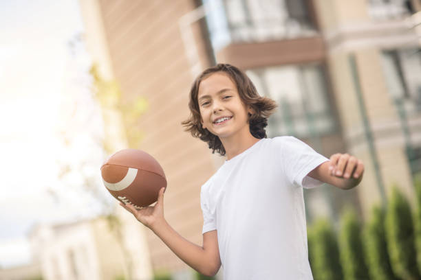 istock Dark-haired boy in a white tshirt playing with a ball 1300008942