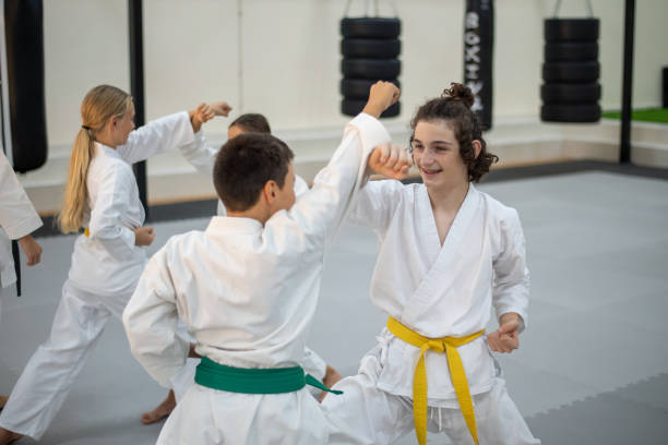 niños caucásicos en kimono practicando karate en un gimnasio deportivo. sesión de entrenamiento de artes marciales - child karate little boys martial arts fotografías e imágenes de stock