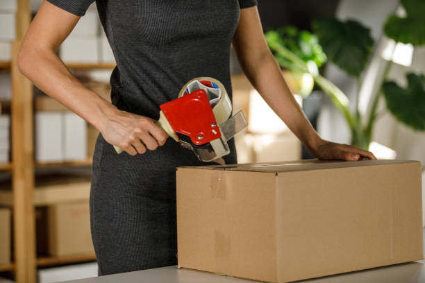 istock Woman taping a cardboard box for a package she is shipping 1300009317