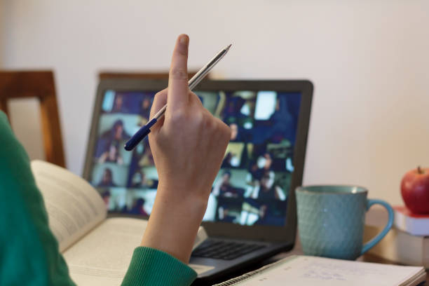 Student taking an online class with his arm raised to ask a question