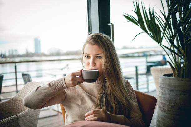 istock young woman drinking coffee at the cafe, looking away 1300018037