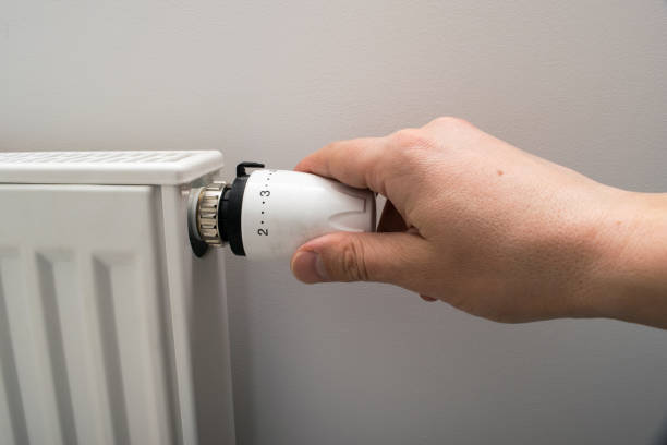 istock Person adjusting thermostat control on a central heating. Temperature control valve on a radiator. 1300018991