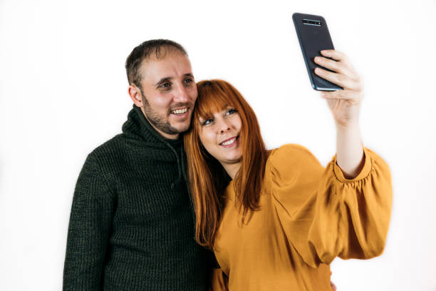 istock Happy couple taking a selfie together on white background 1300019087