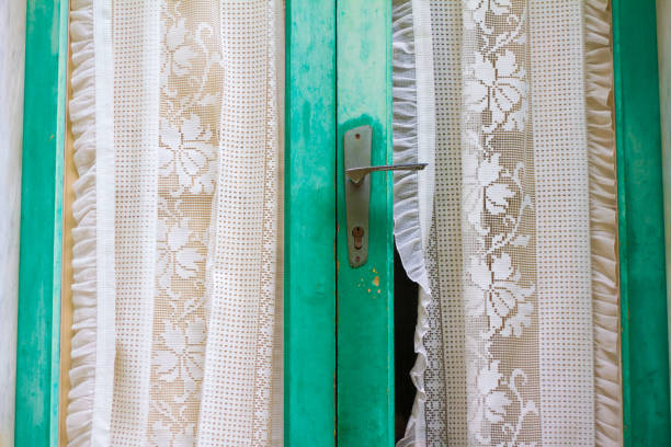 Italy: Rustic Green Wood French Doors with Lace Curtains Close-Up. Shot in Sicily.