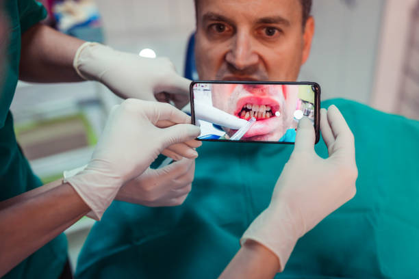 istock Man having his teeth photographed by smart phone at dentist's office 1300019193