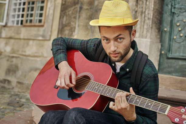 istock Man plays on guitar and sits on sidewalk 1300019462