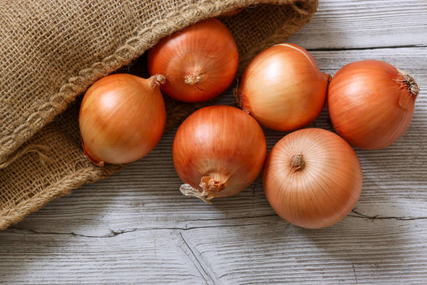 istock onions in a wooden background 1300025102