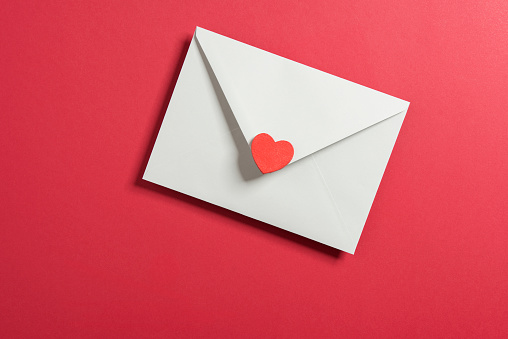Envelope and heart shape on red background.\nHorizontal composition with copy space.\nValentine’s day concept.