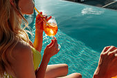 Female in bikini at the swimming pool, drinking cocktail