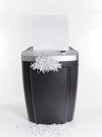 Paper and document shredder on white background with paper and confetti.