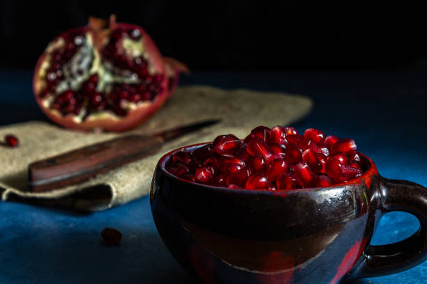 istock Red pomegranate seeds in a cup on a dark background. Close-up. 1300033720